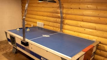 A foosball table in a room with wooden walls and a white brick wall.