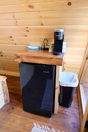 A compact kitchenette with a black refrigerator, a coffee maker, and a trash bin. - Two Person A-frame near Tappan Lake, Ideal to Reconnect with Nature in Ohio (Deersville)