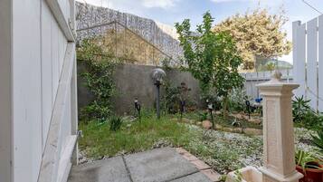 Ein Garten mit einem Kiesweg, einem weißen Zaun und verschiedenen Pflanzen.