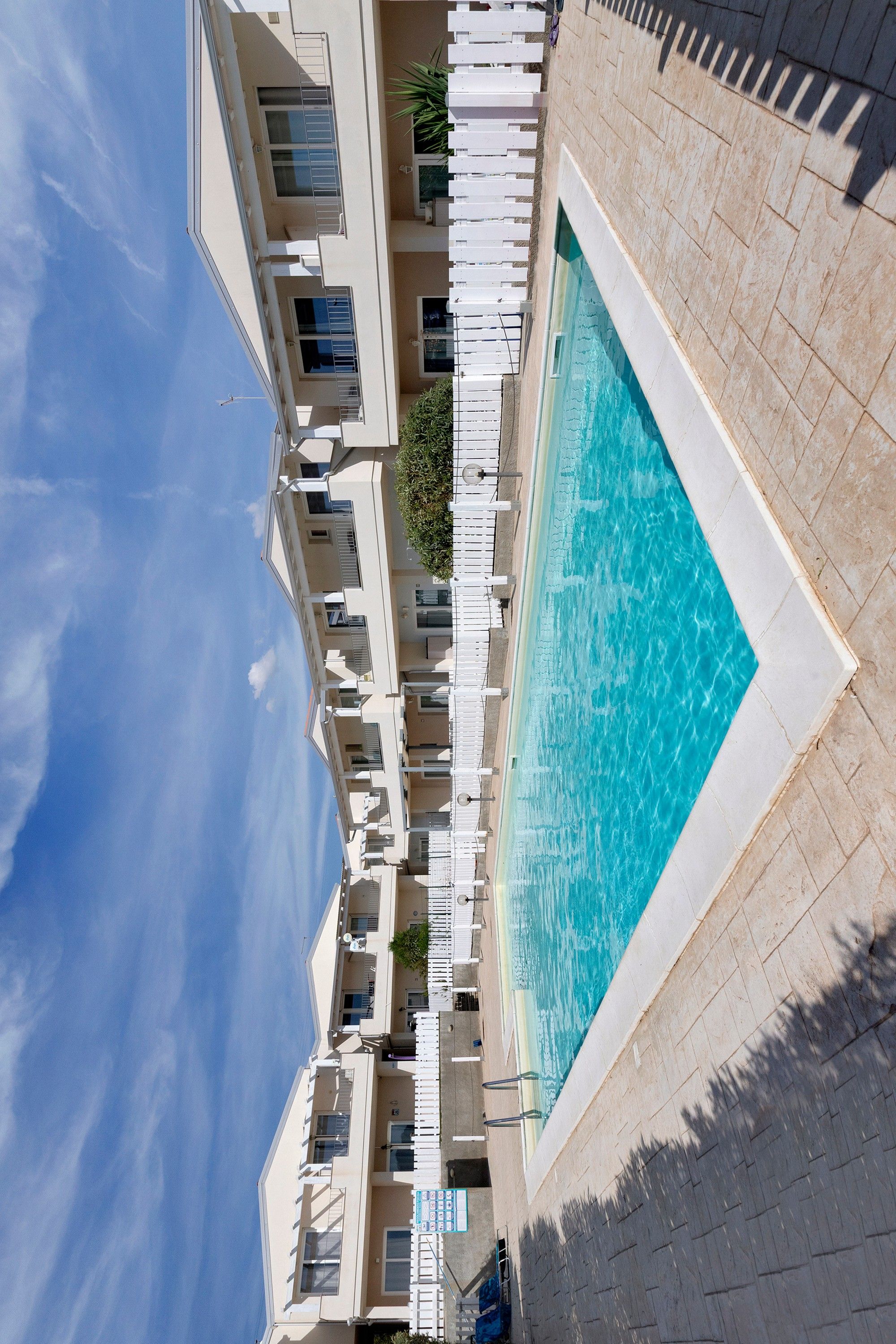 Un edificio moderno con piscina, balcones y cielo despejado.
