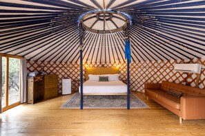 A yurt interior with a bed, a sofa, a chest of drawers, and a small table.