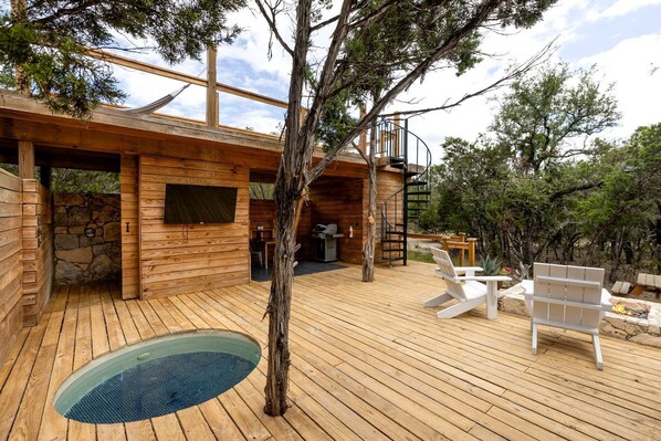 A wooden cabin with a deck, outdoor seating, and a fire pit.