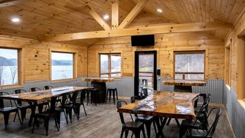 Une cabane en bois avec un coin repas, de grandes fenêtres et une vue sur un lac.