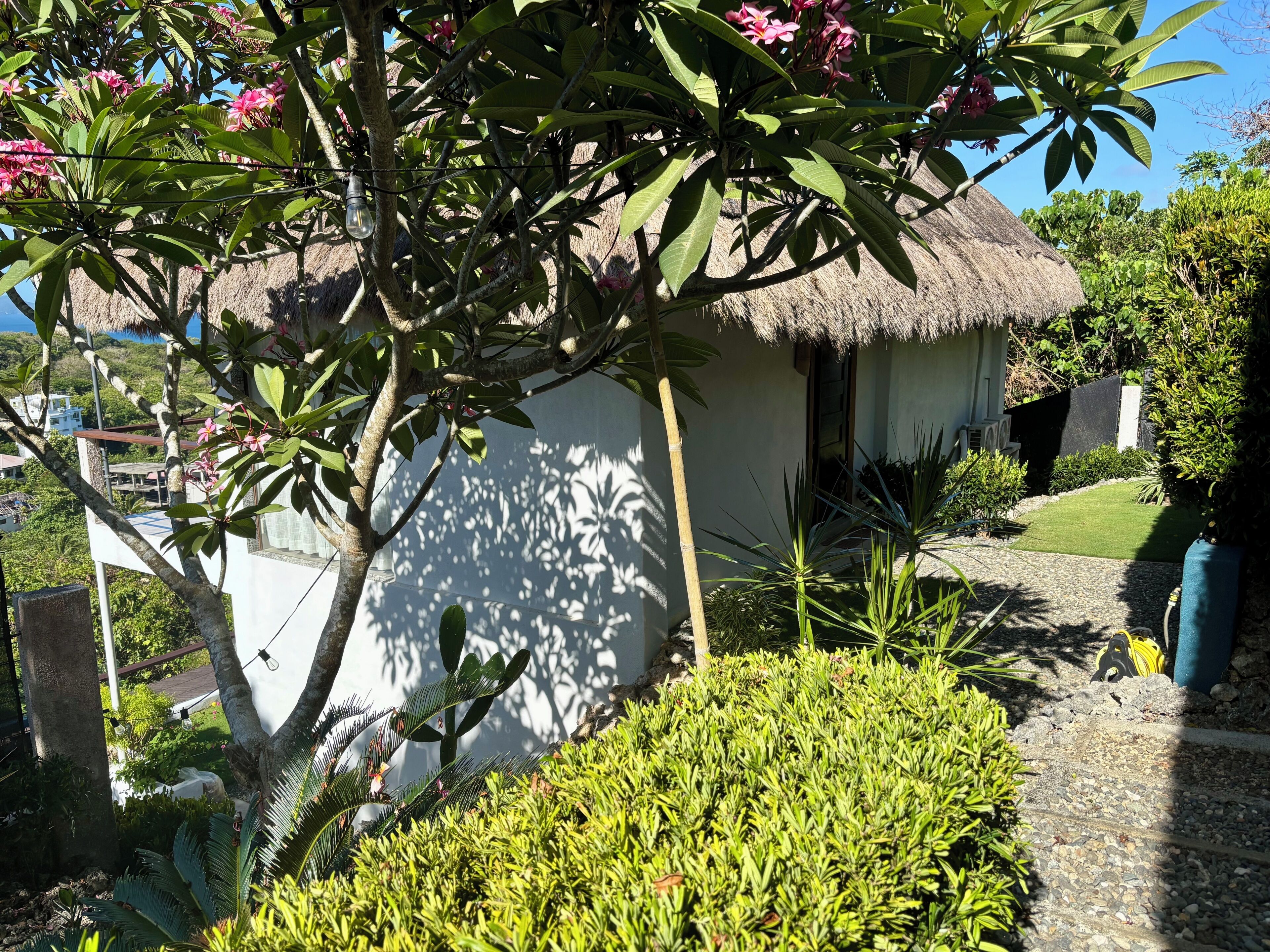 A thatched-roof structure surrounded by lush greenery and a well-maintained garden.