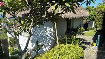 A thatched-roof structure surrounded by lush greenery and a well-maintained garden.