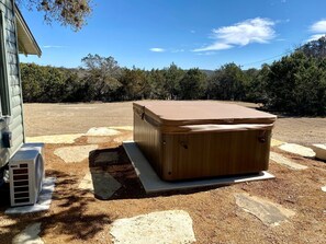 Un jacuzzi dans un jardin, avec une maison et des arbres en arrière-plan.