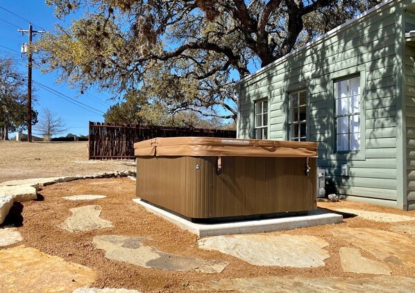 Un jacuzzi situé devant une maison, avec un chemin en pierre menant à l’entrée.