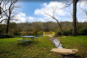 A picnic area with a table and benches, a yellow bridge, and a river in the background.