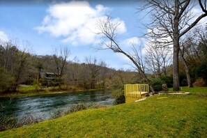 Une rivière avec un quai en bois, des berges herbeuses et des arbres sans feuilles.