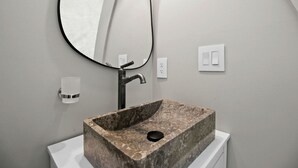 A bathroom with a rectangular stone sink, a modern faucet, a wall-mounted mirror, and a white toilet. - Outstanding Chic Dome with Private Deck in North Carolina (Creston)