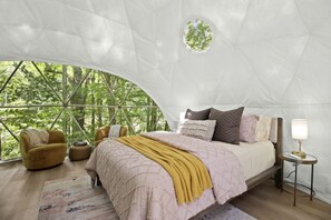 A bedroom with a bed, pillows, a bedside table with a lamp, a chair, and a rug. - Outstanding Chic Dome with Private Deck in North Carolina (Creston)
