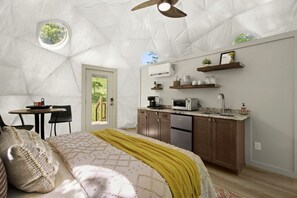 A bedroom with a bed, a window, a door, and a kitchenette with a microwave, toaster, and cabinets. - Outstanding Chic Dome with Private Deck in North Carolina (Creston)