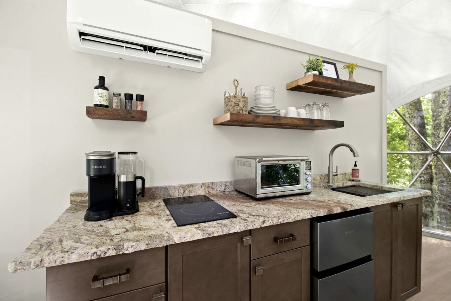 A modern kitchen with a built-in air conditioner, a coffee maker, a toaster, and a sink.