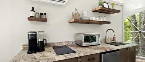 A modern kitchen with a built-in air conditioner, a coffee maker, a toaster, and a sink.