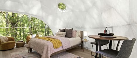 Une pièce spacieuse aménagée comme une tente, avec un lit, un coin salon et une table.