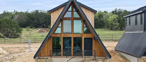 A modern wooden building with a triangular roof, large windows, and a stone base.