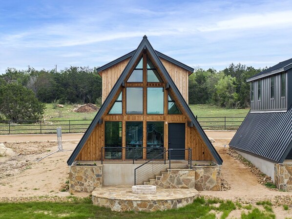 Un edificio moderno de madera con techo triangular, ventanas grandes y base de piedra.