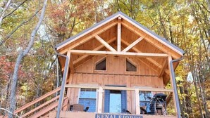 Eine Holzhütte mit Balkon, Treppe und einer Hängematte.