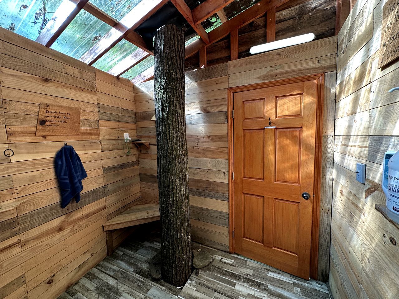 A wooden cabin with a large tree trunk, a wooden door, and a bench.