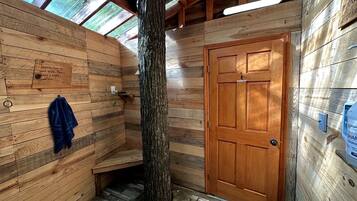 A wooden cabin with a large tree trunk, a wooden door, and a bench.