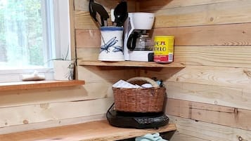 A compact kitchen with wooden walls, a black refrigerator, and a window.