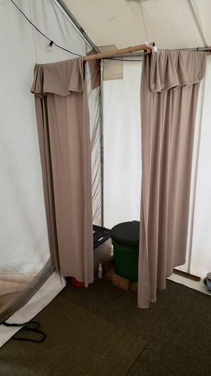 Estructura tipo tienda de campaña con zona de ducha, incluyendo cortinas y cabina de ducha.