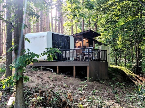 A cabin with a deck, surrounded by trees.