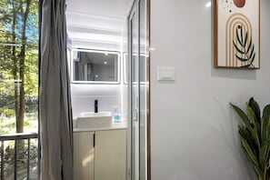 Ein Badezimmer mit einem weißen Waschbecken, einem Spiegel und einer Pflanze.