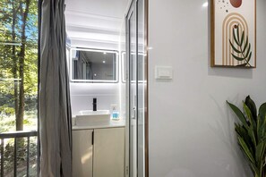 Un baño con un lavamanos blanco, un espejo y una planta.