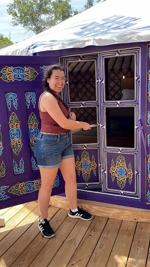 Una persona abre la puerta a un cuarto con fachada morada y detalles ornamentales.