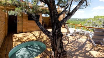 A wooden cabin with a deck, a hot tub, and outdoor seating.