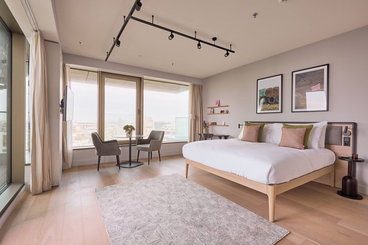 Een moderne slaapkamer met een groot bed, een bureau en een stoel bij een raam.