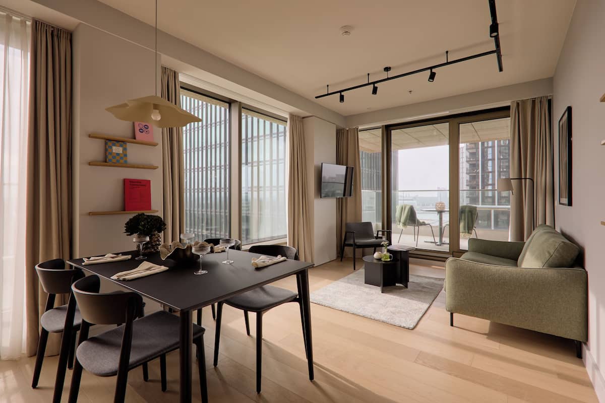 Een moderne woonkamer met een eetgedeelte, grote ramen en stadszicht.