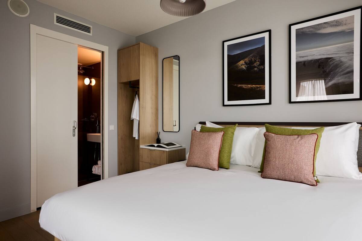 Een hotelkamer met een bed, een kledingkast, een nachtkastje en twee ingelijste foto's aan de muur.