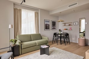 Un salon moderne comprenant un canapé, une table à manger, des chaises et une petite table d’appoint agrémentée d’une plante.