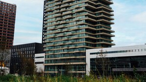 Un immeuble moderne de grande hauteur, doté d’un design original en zigzag, de nombreux balcons et de grandes fenêtres.