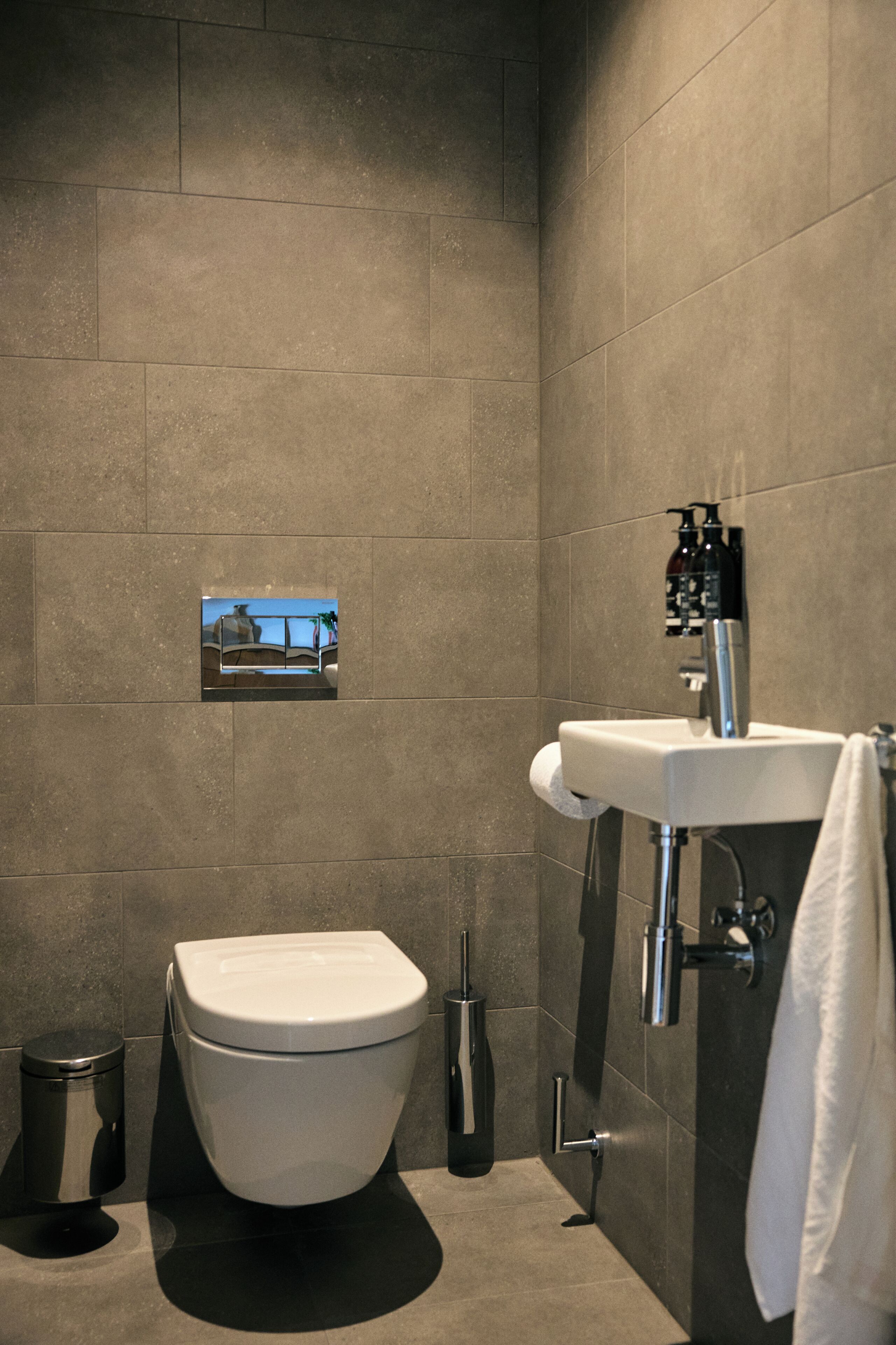 A modern bathroom with a toilet, sink, and a small framed picture on the wall.