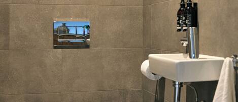 A modern bathroom with a toilet, sink, and a small framed picture on the wall.
