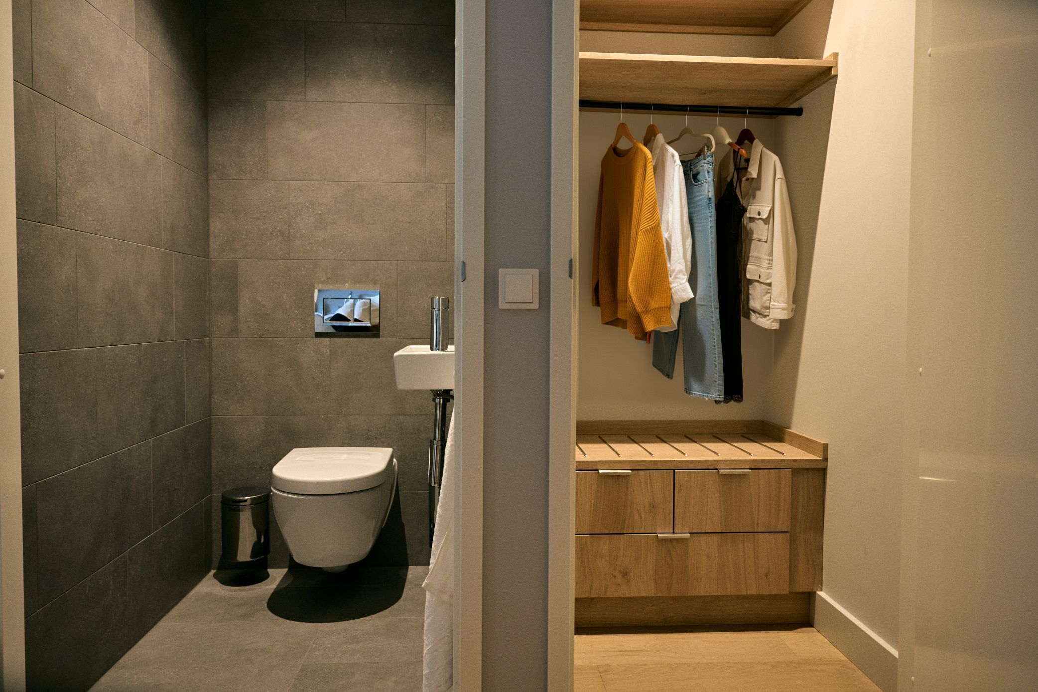 Een moderne badkamer met toilet, wastafel en houten opbergmeubel.