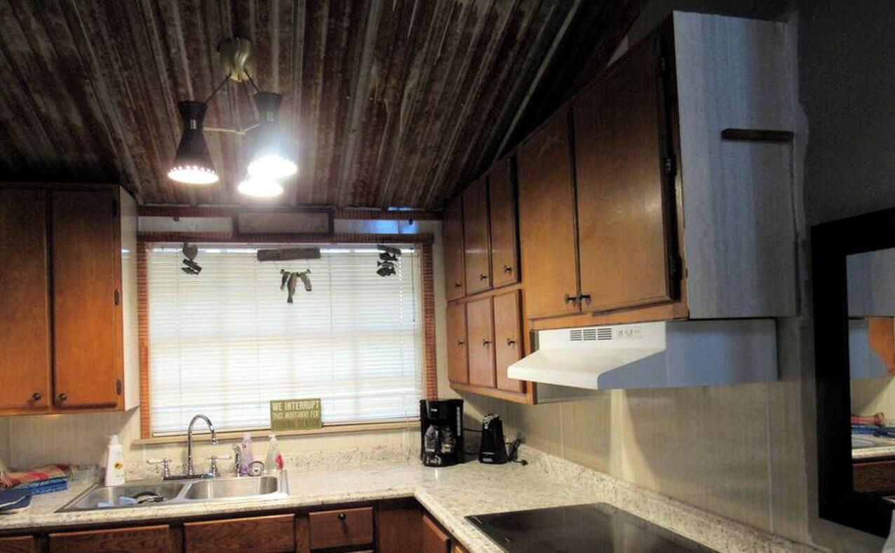 A kitchen with wooden cabinets, a stainless steel sink, and a built-in oven.