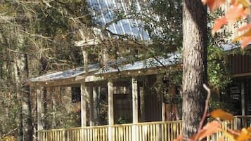 A wooden cabin with a balcony, surrounded by trees.