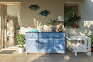 Een blauwe kast met decoratieve vissen, een potplant en een klein tafeltje met wielen.