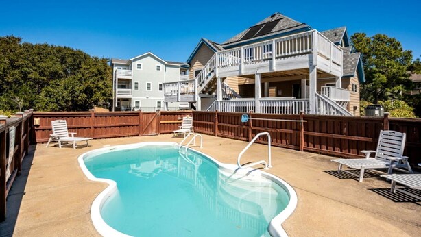 Un cadre résidentiel doté d’une piscine, de mobilier d’extérieur et d’une maison à deux étages avec un balcon.
