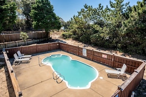 A backyard with a swimming pool, wooden deck, and lounge chairs. - Pet Friendly Coastal Cottage in Corolla, North Carolina, Complete with Outdoor Pool and Private Hot Tub (Corolla)