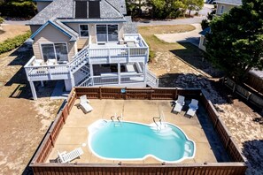 Une maison à deux étages avec une terrasse à l’arrière et une piscine.
