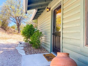 A house with a door, a small bush, a stone pathway, and a large pot.