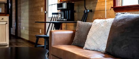 Un salon confortable avec un canapé en cuir, une machine à café et un décor intérieur en bois.