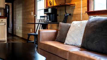 A cozy living area with a leather sofa, a coffee machine, and a wooden interior.