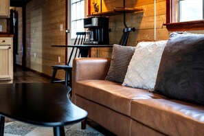A cozy living area with a leather sofa, a coffee machine, and a wooden interior.