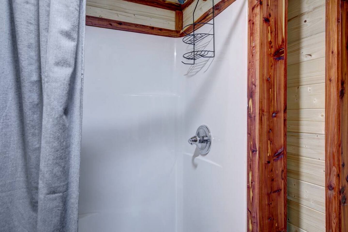 A shower with a wooden frame, a towel, and a metal rack.